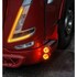 Roter LKW mit eingeschalteten orangen Positionsleuchten und zwei runden orangen Zusatzleuchten.